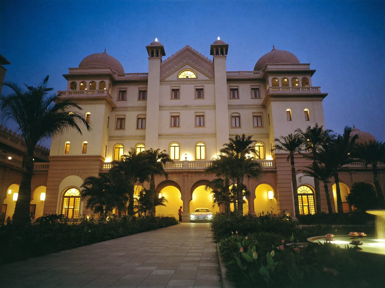Grand Indian palace hotel in Bengaluru at blue hour, domes and palm-lined driveway